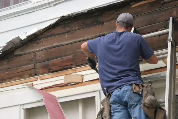 a man removing the old vinyl siding