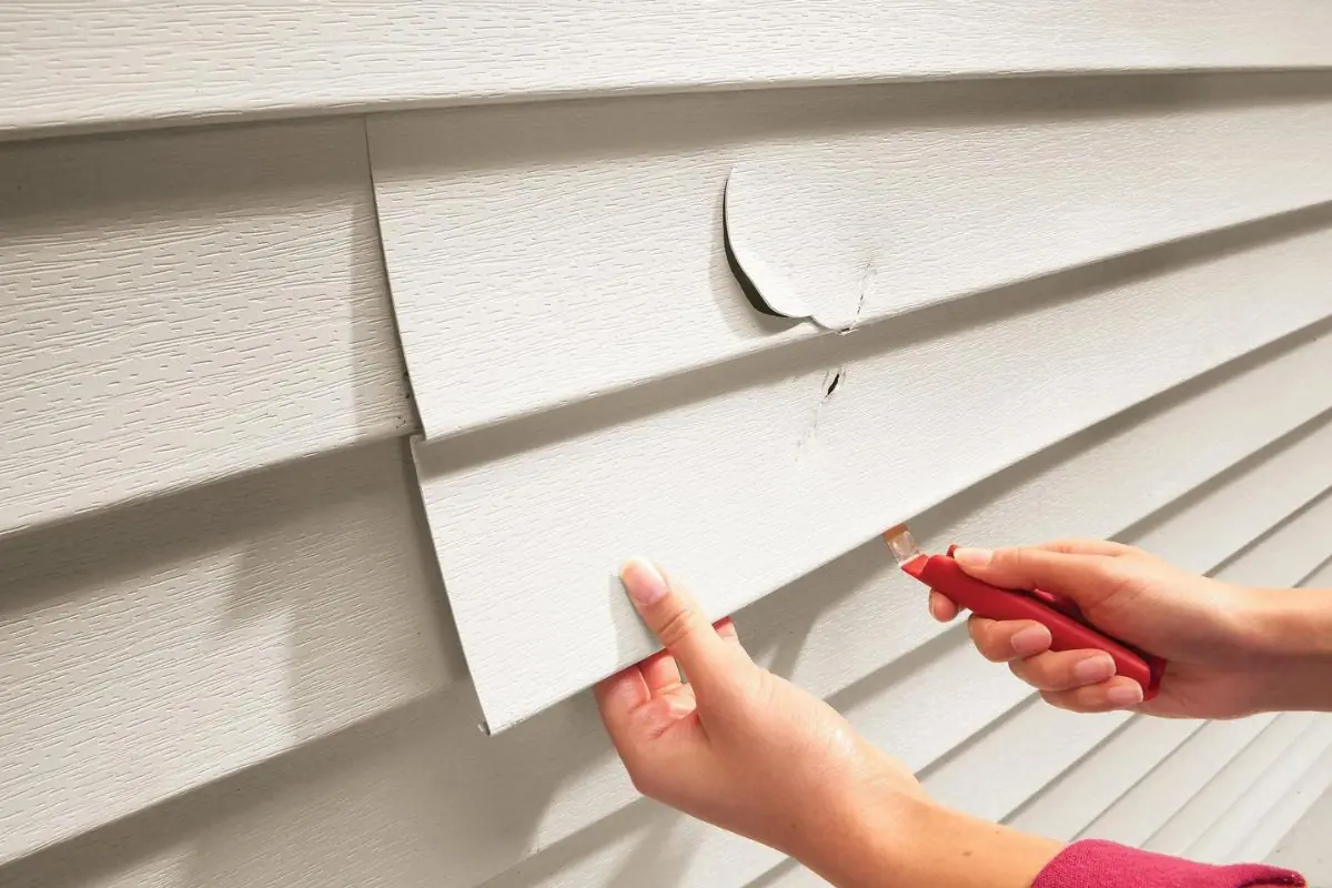 two hands replacing the old vinyl siding