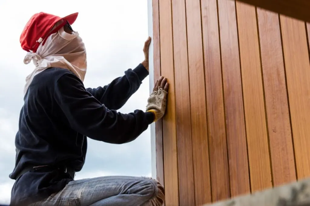 man installing vertical wood siding